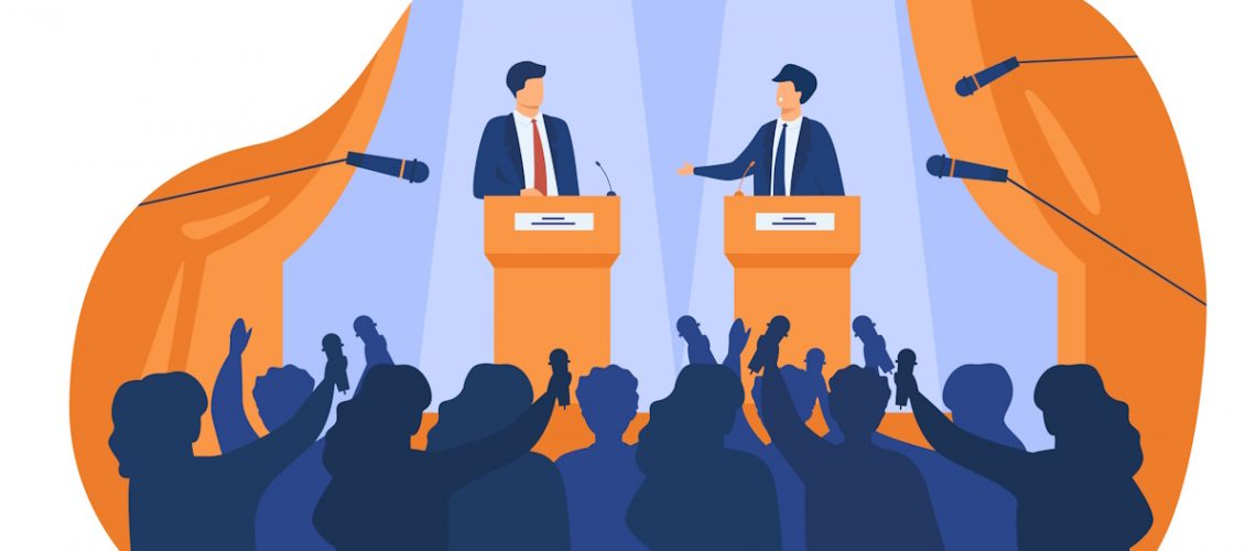 Two politicians are having a debate in front of an audience, holding microphones.
