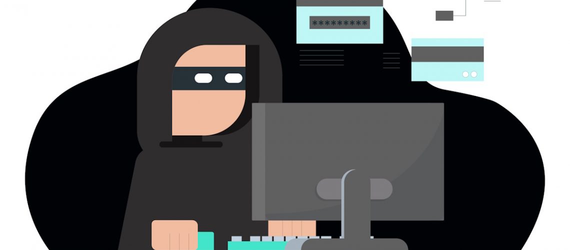 A masked criminal wearing a hoodie using a computer.